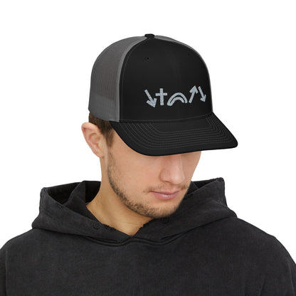 A young man wearing a black and charcoal trucker cap with five gospel symbols displayed on the front. He is dressed in a dark hoodie, and the background is a plain white, highlighting the hats design and colors.