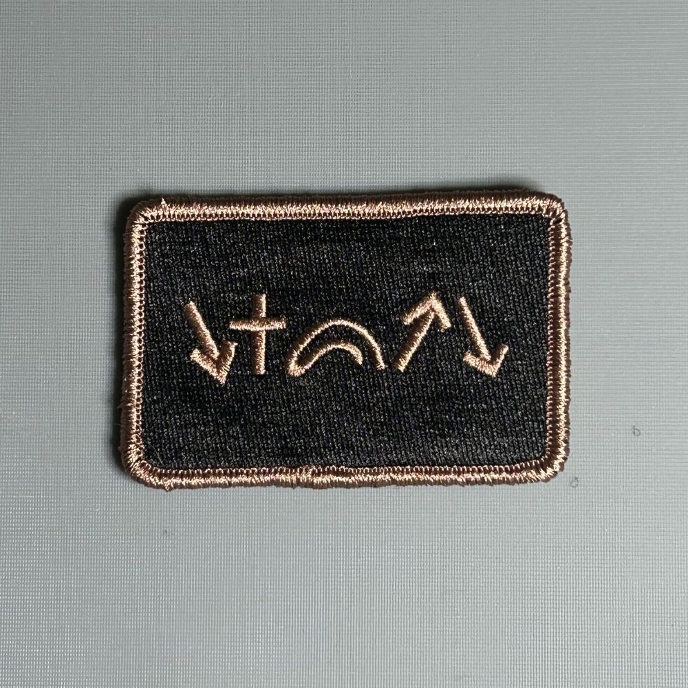 A rectangular black Velcro patch with green and beige embroidery depicting five gospel symbols.