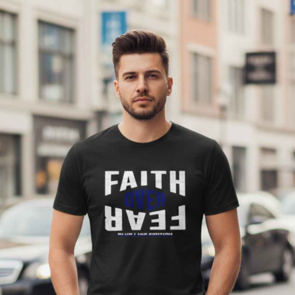 Man wearing a black t-shirt with 'Faith Over Fear' text on a city street.