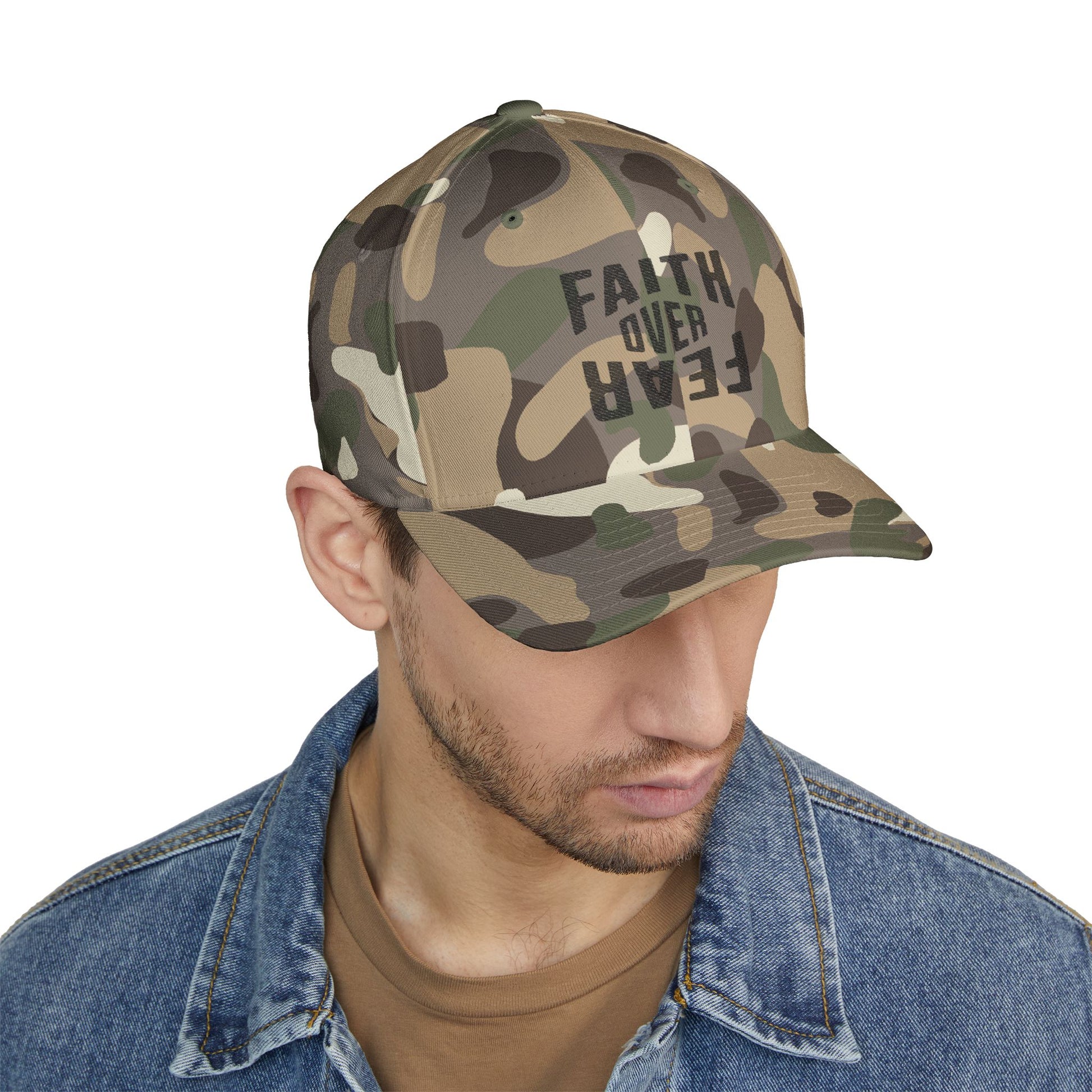 Camouflage cap with 'Faith Over Fear' text worn by a person on a white background
