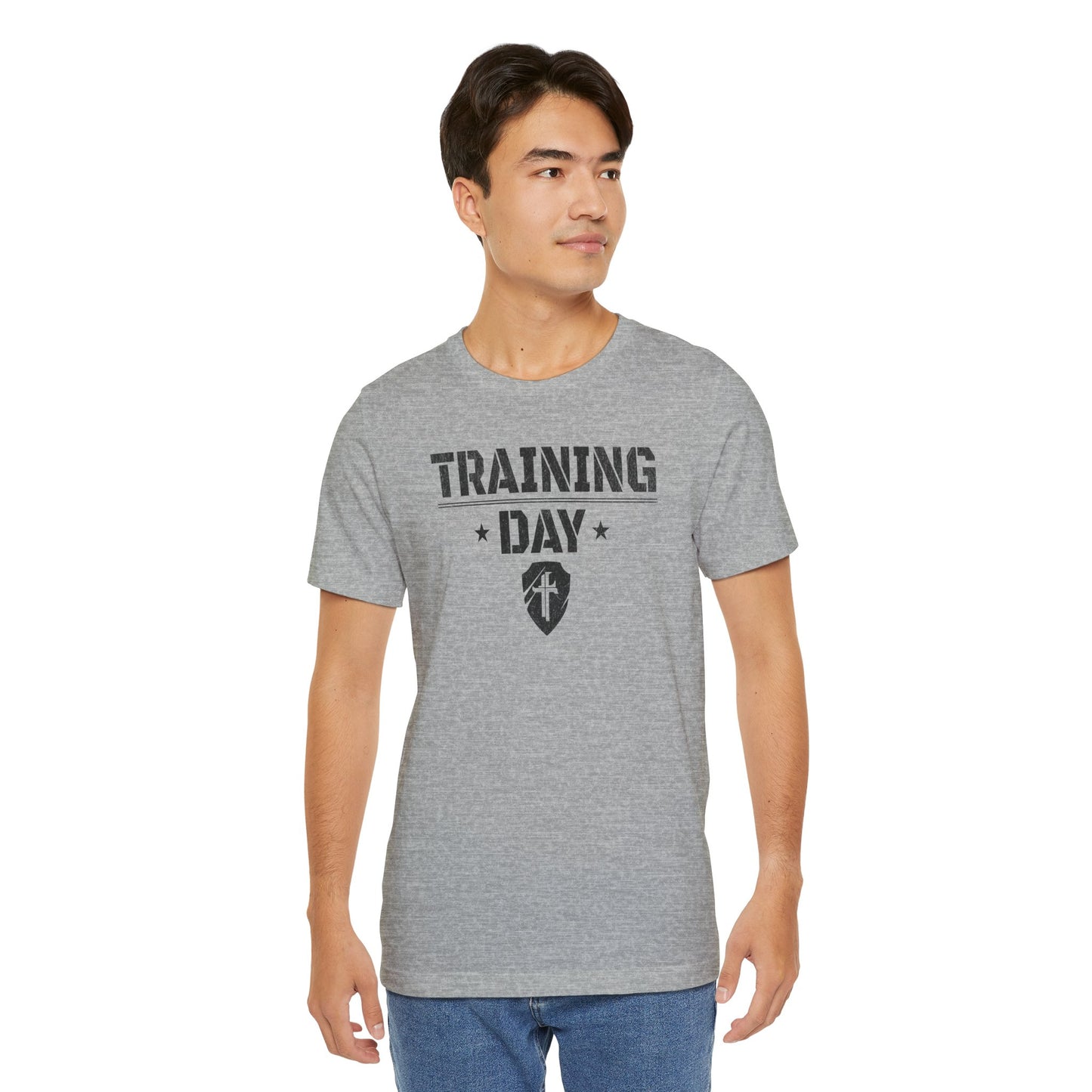 A person wearing a gray T-shirt with the text 'TRAINING DAY' and a shield with a cross on it.